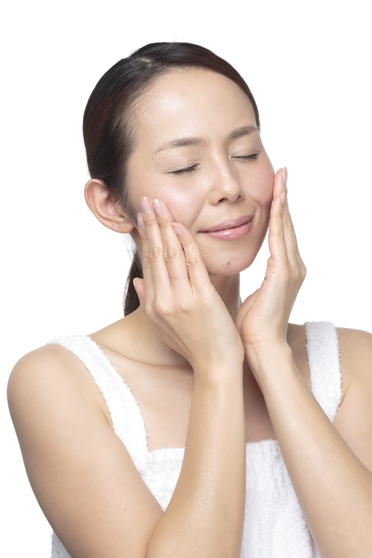 両手で頬を包み、肌の仕上がりを確かめる女性